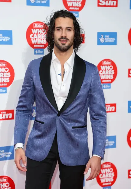 Man in blue patterned jacket at awards ceremony.