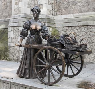 Bronze statue of Molly Malone with a wheelbarrow and baskets.