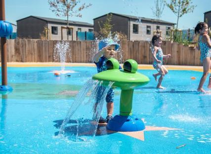Toddler playing in a splash pad with frog-shaped water feature.