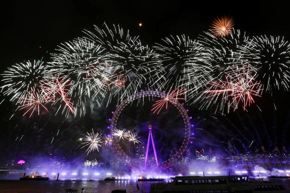 Fireworks exploding around the London Eye Ferris wheel over the River Thames.