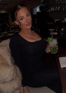 Woman in black dress holding a mojito.