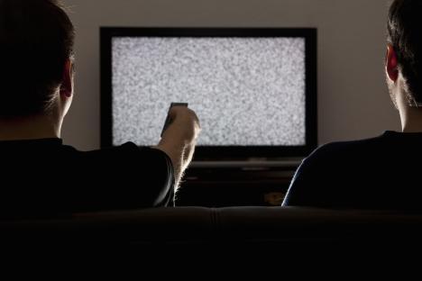 Two men watching a television screen displaying static.