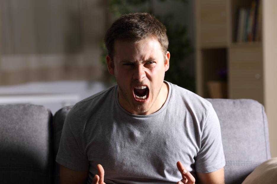 Furious man shouting while looking directly forward.