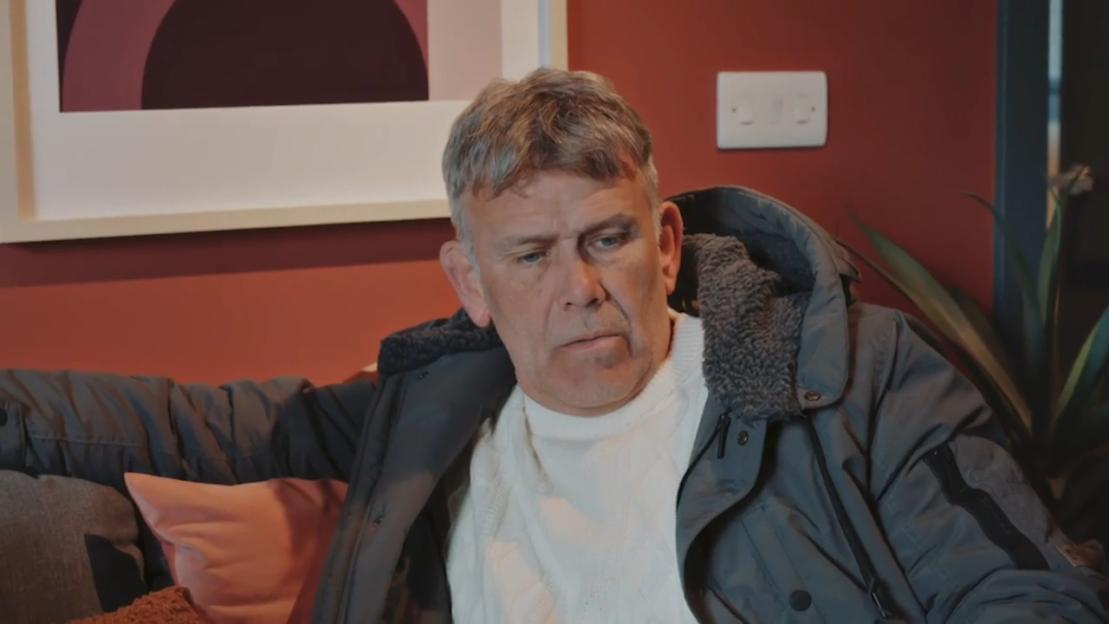 Paul, looking disappointed, in a dark jacket and white sweater.