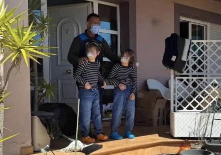 Police officer with two young boys outside a house.