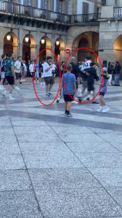 Video still showing Tottenham and Manchester United fans arguing and kicking a football at each other in a plaza.