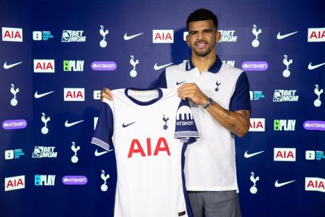 Dominic Solanke holding a Tottenham Hotspur jersey at a press conference.