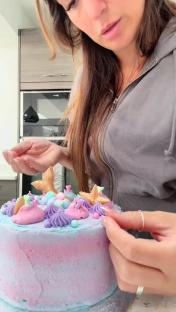 Person decorating a pastel mermaid-themed cake.
