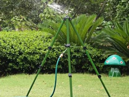 Tripod lawn sprinkler spraying water.