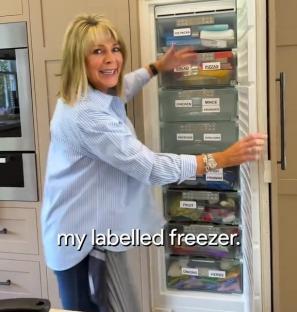 Woman standing in front of a freezer with labeled drawers.