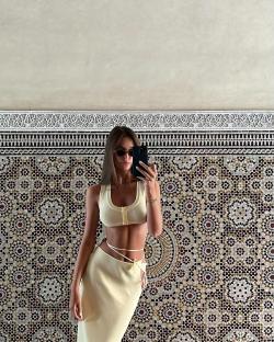 a woman taking a picture of herself in front of a mosaic wall