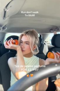 Woman in car smelling and showing a £2.99 B&M perfume dupe.