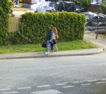 Two teens walking on a sidewalk.