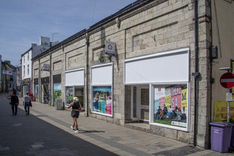Closed shops in Bangor, Wales, with Gwynedd council posters.