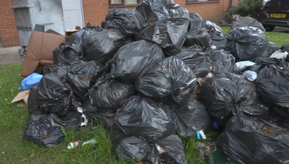Large pile of black garbage bags on the ground.