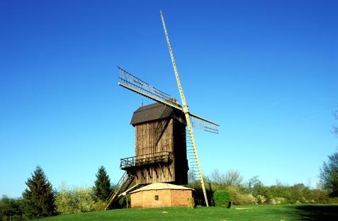 Wooden windmill against a blue sky.