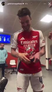 Arsenal player holding a trophy in the locker room.
