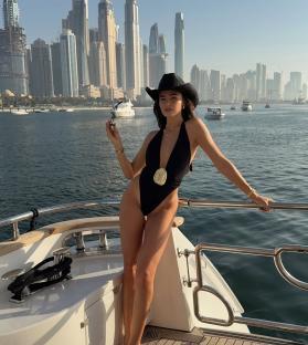 Woman in black swimsuit and cowboy hat on yacht in Dubai.