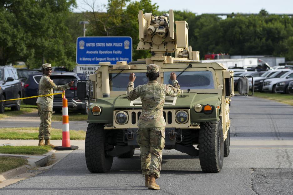 Military personnel guiding a Humvee out of the U.S. Park Police Anacostia Operations Facility.
