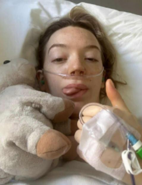 Injured woman in hospital giving thumbs up.