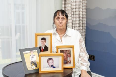 A woman sits with framed photos of her deceased son and his brother.