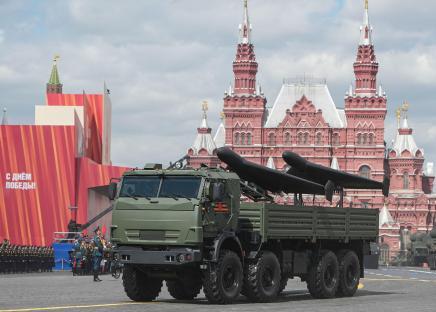 Armored vehicle carrying drones in a military parade.