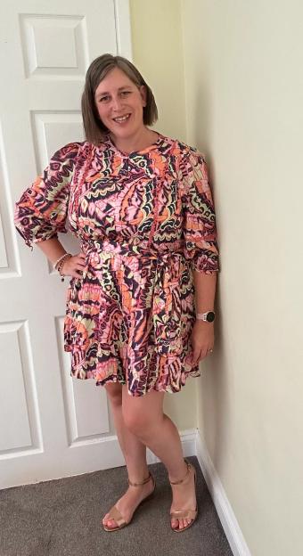 Woman in patterned dress and gold sandals.