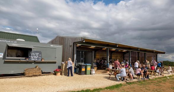 Customers eating and drinking at an outdoor farm shop.