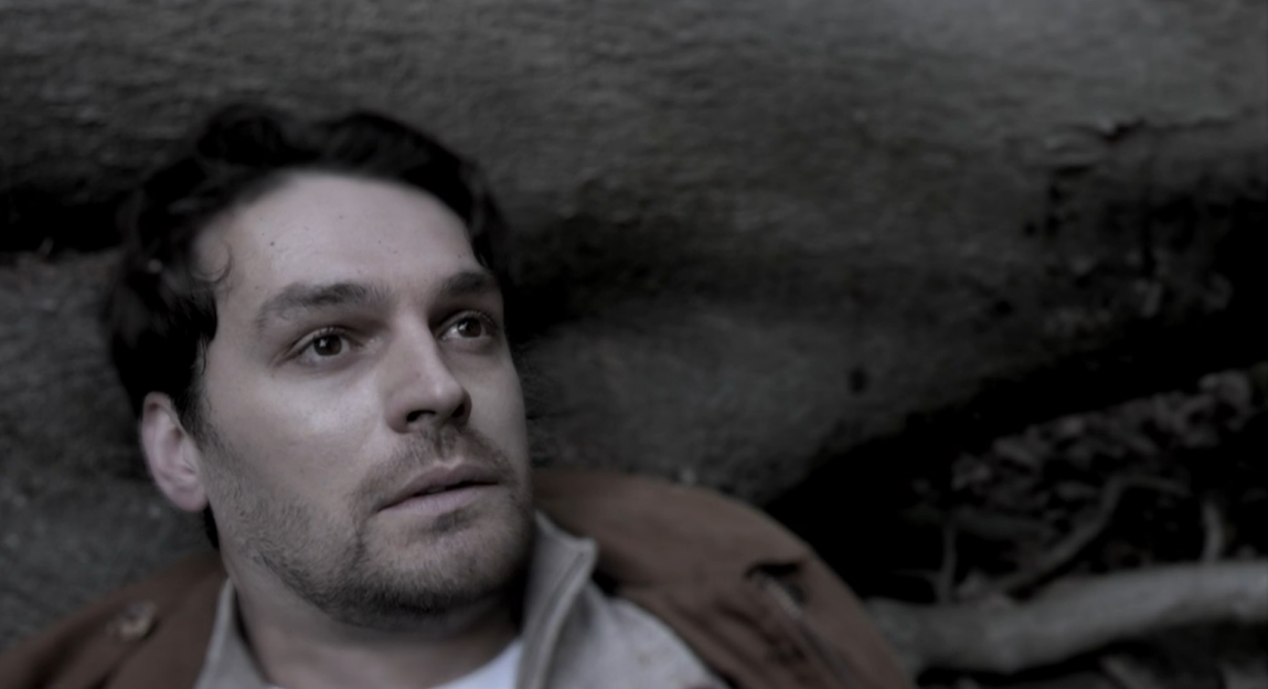 A bloodied man lying on the ground.
