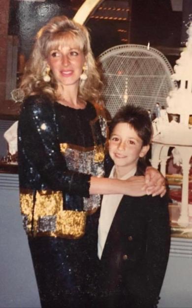 a woman in a sequined jacket holds a young boy in a suit