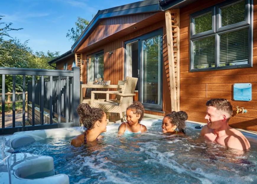 Family relaxing in a hot tub outside a cabin.