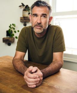 Portrait of a man sitting at a wooden table.