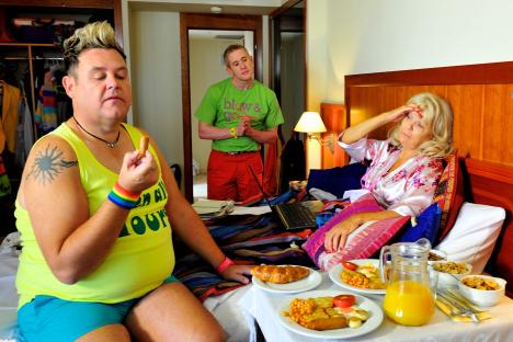 Three actors from the TV show Benidorm; one eating breakfast, one standing, and one in bed.