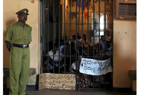 Guard standing outside an overcrowded prison cell in Sri Lanka.