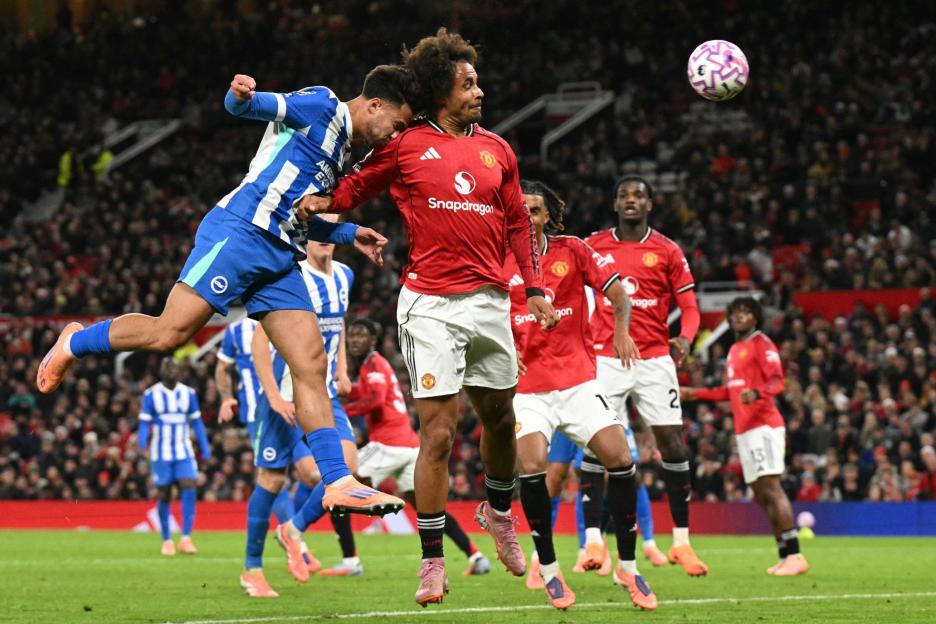 Brighton & Hove Albion player heading the ball against Manchester United players.