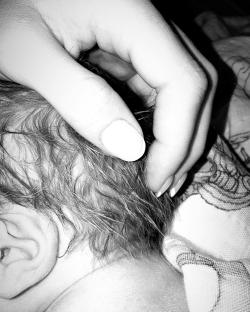 Hand gently touching a baby's head.