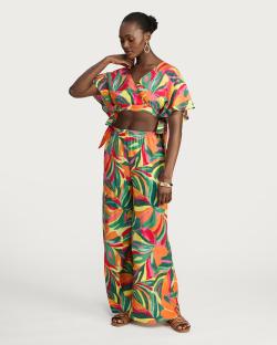 Woman wearing a colorful tropical print crop top and wide-leg pants.