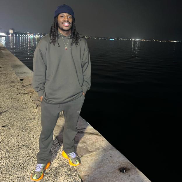 A man smiling by the water at night.