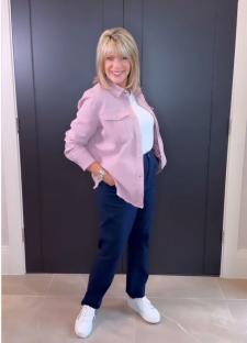Ruth Langsford modeling a pink shirt and dark pants.