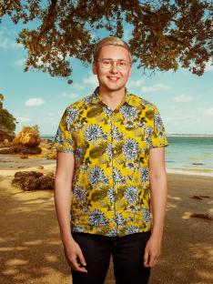 Man in floral shirt on beach.