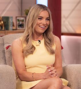 A man and woman smiling at the camera while enjoying pizza and drinks outdoors.