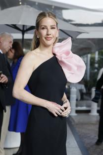 Ellie Goulding wearing a black one-shoulder dress with a pink flower detail at the shoulder.
