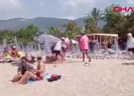 A person being attacked on a busy beach.