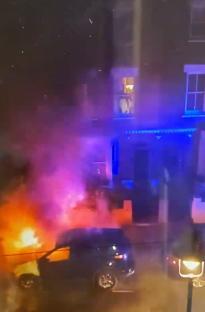 Screengrab of firefighters extinguishing a burning car.