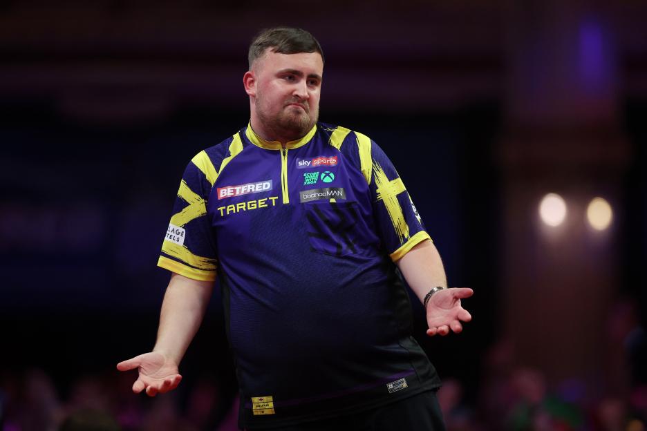 Luke Littler of England celebrates a '9 dart finish' during a darts match.