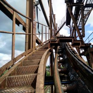 Rusty roller coaster tracks and stairs in an abandoned theme park.