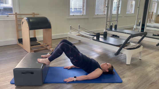Woman performing a Pilates exercise on a reformer.