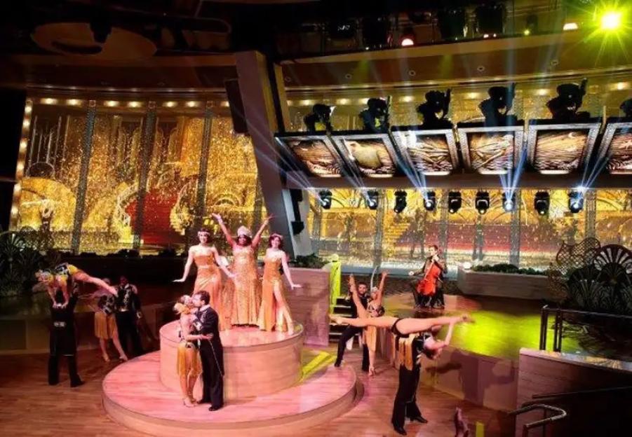 Performers on a stage with a golden art deco backdrop on the cruise ship Quantum of the Seas.