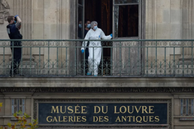 Law enforcement personnel in protective gear on a balcony of the Louvre Museum.