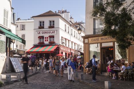 Busy Parisian street scene with cafes and pedestrians.